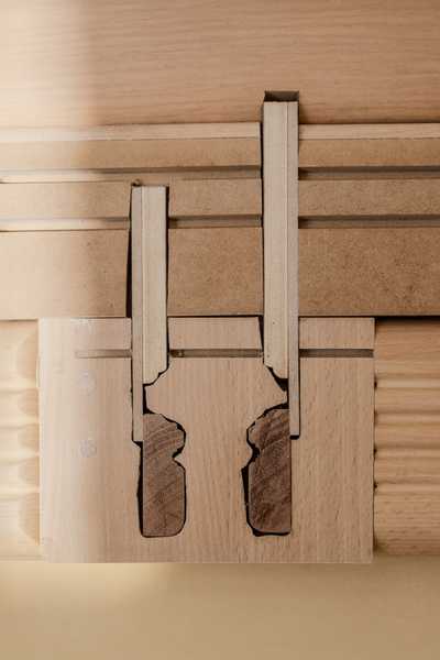  Installation view of Charms (2025) by Julia Rosenstock: a 30-minute video projected within a custom frame, accompanied by two-channel sound transmitted through resonant surfaces in the gallery. A bench sits in the space alongside wall-mounted reliefs made from plastic foil-coated MDF with walnut and oak veneer.