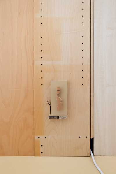  Installation view of Charms (2025) by Julia Rosenstock: a 30-minute video projected within a custom frame, accompanied by two-channel sound transmitted through resonant surfaces in the gallery. A bench sits in the space alongside wall-mounted reliefs made from plastic foil-coated MDF with walnut and oak veneer.